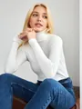 Eleganter weißer Rippen-Rollkragenpullover für Damen an einem sitzenden Model - Einheitsgröße / Oberteile / Weiß