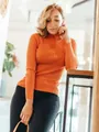 Women's orange slim fit ribbed turtleneck sweater shown in a bright lifestyle setting. - One Size / Tops / Orange