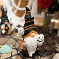 Close-up detail view of a Halloween gnome resin ornament holding ghost and pumpkin masks - Striped Hat With Ghost Style