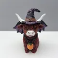Vista detallada de una figura de vaca Highland de Halloween con sombrero de bruja púrpura - Vaca de las Tierras Altas con Alas de Murciélago y Sombrero de Bruja Púrpura