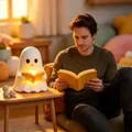 Cozy lifestyle view of a cute ghost-shaped reading book night light on a side table. - White