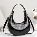 Elegante schwarze glänzende Halbmondtasche mit Krokodilmuster und Golddetails - 21cmx6cmx21cm / Schwarz