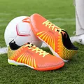 Bright orange and yellow men's TF turf soccer shoes on a green grass football field - 36 / Orange (M720)