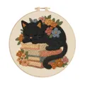 Detailed view of finished black cat embroidery on a stack of books with floral accents - Black Cat Books And Flowers (Style E)
