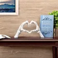 Close-up detail of a creative Halloween skeleton heart hand resin ornament on a table. - S / White