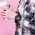 Primer plano de un reloj deportivo digital negro usado en la muñeca con fondo de camisa a cuadros - Negro