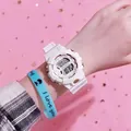 Vista detallada de un moderno reloj deportivo digital blanco con pulsera de silicona azul. - Blanco
