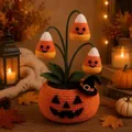 Makroaufnahme eines handgehäkelten Halloween Kürbis-Topfes mit Zuckermais-Glockenblumen - Bonbon