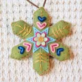 Detailed view of hand-embroidered green felt snowflake ornament with colorful motifs. - Green Snowflake (202640) / Green DIY Kit