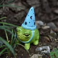 Vista detallada de una rana verde con sombrero de mago azul en un entorno de jardín natural. - Rana Con Gorro de Navidad (Azul) / Estilo de Sombrero Puntiagudo Azul