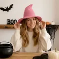 Woman wearing a pink knitted wizard hat in a festive Halloween room setting - Pink