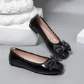 Detail view of black patent leather ballet flats with large fabric bow decoration. - 35 / Black