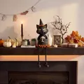 Detailed view of Halloween black cat figurine holding a skull on a cozy fireplace mantel - Black Cat