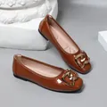 Detailed shot of brown patent leather ballet flats with a stylish gold-tone buckle - Tan
