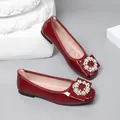 Close-up of elegant red patent leather ballet flats with pearl circle buckle decoration. - Burgundy