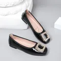 Detailed close-up of black patent leather flats with an elegant rhinestone square buckle. - 35 / Black