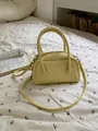 Chic lemon yellow pebbled leather pillow bag with crossbody strap on a floral bed. - Yellow