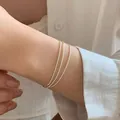 Close-up of a delicate three-layered silver beaded bracelet worn on a wrist. - Triple Layer Stacked Bead Chain Style (MY36162)