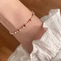 Close-up of minimalist silver bracelet with delicate red beads and ruffled white sleeve - Red Bead and Silver Tube Beaded Style (MY35808)