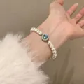 Detail shot of an elegant pearl bracelet featuring a central blue zircon worn on the wrist. - Artificial Pearl Rhinestone Blue Pendant Style (MY35575)