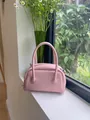 Detailed view of pink pebbled leather pillow bag on a sunlit windowsill - Pink