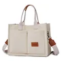 Detailed view of cream canvas tote bag featuring front pockets and brown leather trim - H 25cm W 14cm L 34cm / Off White
