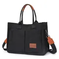 Close-up of black canvas tote bag showing front pockets and leather brand label - H 25cm W 14cm L 34cm / Black