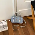 Chic blue denim bowling bag with metallic silver handles and adjustable shoulder strap - Silver