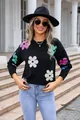 Close-up view of a black knit sweater featuring vibrant colorful flower patterns - S / Tops / Black