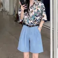 Close-up detail of stylish floral print shirt and blue high waist shorts with belt - S / Bottoms / Blue