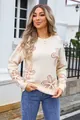 Detail view of the floral pattern on a cream long-sleeved crew neck knitted sweater - Apricot and Camel