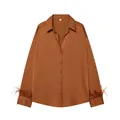 Vista frontal de una blusa de satén bronce con lujosos puños de plumas suaves. - XS / Tops / Marrón