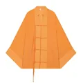Detail van de knoopsluitingen en de getextureerde oranje stof van het soepele shirt. - Oranje