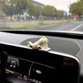 Miniature healing cat figurine car ornament reading on dashboard screen detail view - Prone Reading Cat