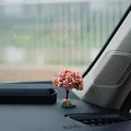Detailed close-up view of a miniature pink artificial tree ornament on a car dashboard - Wishing Tree
