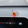 Close-up view of a miniature iced coffee car ornament placed on the center display screen - Ice Black Tea
