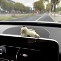 Close-up detail of a cute lazy cat figurine decoration placed on a car dashboard screen - Side Lying Cat