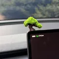 Close-up of a miniature artificial bonsai tree ornament on a car dashboard screen - Wishing Tree