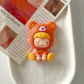 Détail en gros plan d'une figurine de fille en résine avec un costume d'ours orange - Costume d'Ours Orange