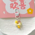 Macro view of a cute donut cat keychain with white metal clasp on a pink background. - Yellow Brown Cat
