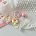 Close-up of cute pink cat donut keychain with bell on white fringe blanket - Cream Pink Cat + Pink Ring + Pink Bell