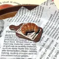 Detailansicht eines realistischen 3D-Croissant-Kühlschrankmagneten aus Harz auf Holz - Croissant Kühlschrankmagnet