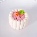 Nahaufnahme eines 3D-Kuchen-Kühlschrankmagneten mit rosa Glasur und Sahnetextur. - Weiß