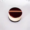 Detailaufnahme eines 3D-Miniatur-Kuchen-Kühlschrankmagneten mit roter Glasur und Cremeschichten - Kaffeebraun