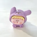 Close-up van een miniatuurhars Liz-beeldje in een paarse puppy-hoodie voor DIY - Paars