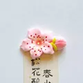 Detailed macro view of a pink cherry blossom resin refrigerator magnet on a paper strip - Blooming Flower with Bud / 6.8x4.5cm