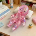 Pink translucent glittery baby squishy toy for stress relief shown on a wooden desk - OPP Bag / Pink