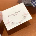 Sweet pink fabric bow stud earrings with heart stones and pearls on white display card - Light Pink Bow Ribbon (3 Pairs)