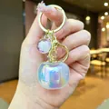Macro view of a cute iridescent persimmon keychain pendant held in hand for bag decoration - Quantity 1 is 1 Unit / Bubble Gold [White] Electroplated Persimmon