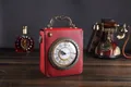 Sac à main vintage rouge en forme d'horloge avec poignée antique sur table en bois - Rouge